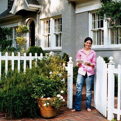 若い homeowner in front of her painted brick house with a white picket fence in front