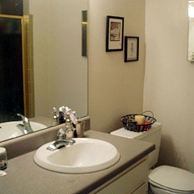 ل outdated bathroom with gray formica countertops and a mirror before it is to be renovated