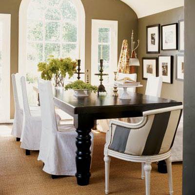 クラシック and stylish dining room with a large black table with white, slip-covered chairs surrounding it and a striped arm chair at the head of the table