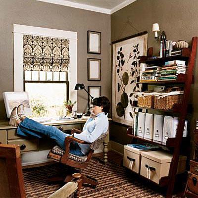 А desk is positioned in front of the window in this home office, while ladder shelving with decorative storage containers are organized on the opposite wall. Chocolate brown walls and black, brown and cream window treatment completes the look of this work