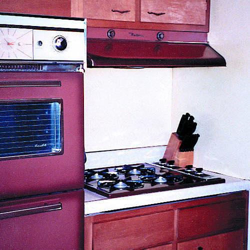 時代遅れの kitchen cabinets with an old oven and stove in burgundy colors