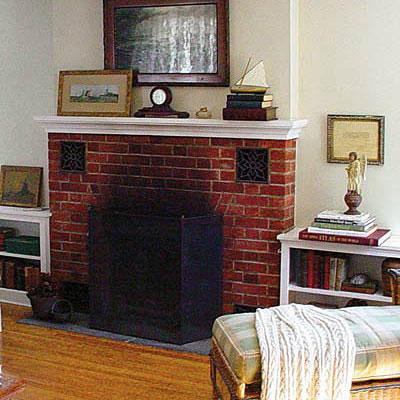 а before photo of a old brick fireplace with blackened bricks in a family room with white walls