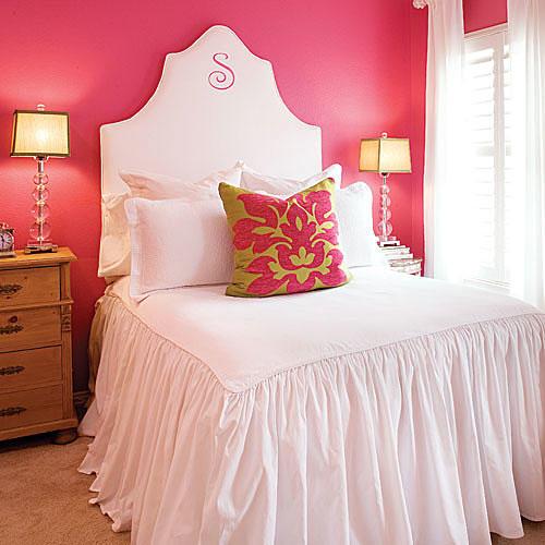 明るい pink-coral paint on the wall off-sets a white, fabric headboard with a gathered comforter on the bed giving a tropical feel to the decor