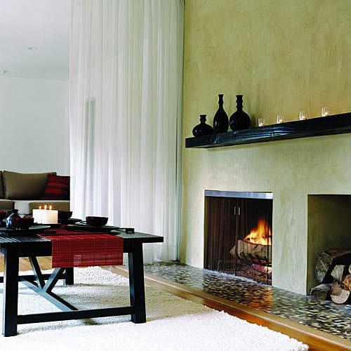 洗練された、 stucco-covered fireplace with a dark wood mantel and a storage place for a stack of wood in this lounge space