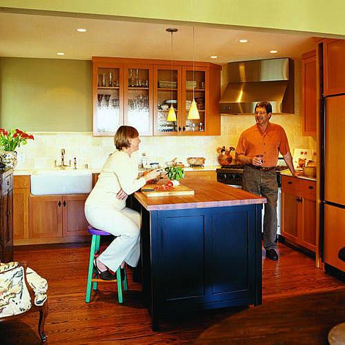 معاصر kitchen with avocado green walls, warm oak cabinets and a kitchen island in the middle with a wooden countertop and black painted underneath