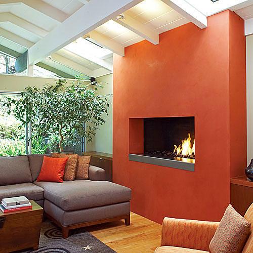 А vibrant tomato bisque-hued plaster added to this fireplace remodel turned the hearth into a modern showpiece in this living room.