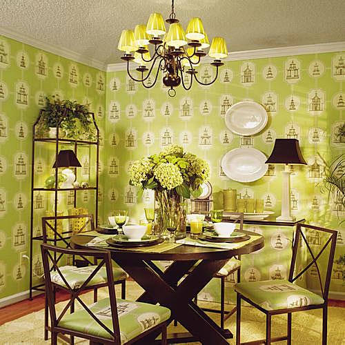 後 photo with a dining room that’s wallpapered in pale, green Asian designs, and a dark wood dining room table in the middle of the room set with china (and chairs surrounding it). 