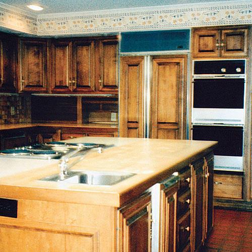 المتضخم kitchen island with brown cabinets with an old oven and old florescent lighting in the ceiling