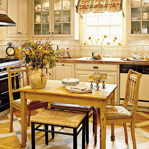 ا renovated kitchen with natural wood breakfast table with two chairs, creamy kitchen cabinets with glass panels and copper countertops 