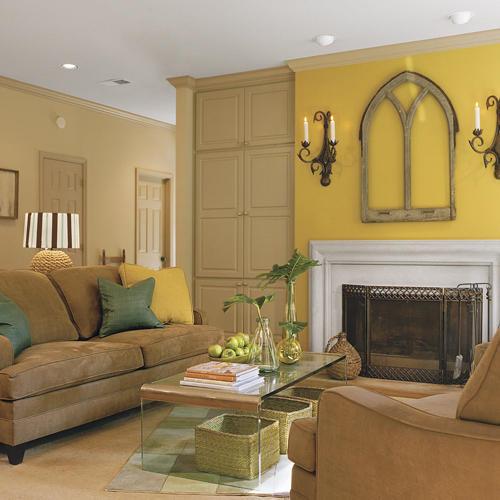 жълт walls highlight the artwork above the family room fireplace while the couch faces a clear, glass, mod coffee table