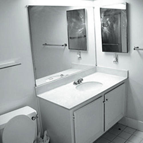 черно and white photo of a plain bathroom with a sink in a simple cabinet with a wall mirror above