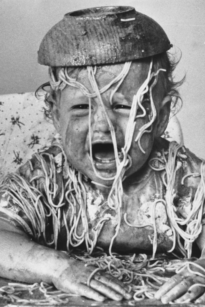 Bebé covered in spaghetti with bowl on head