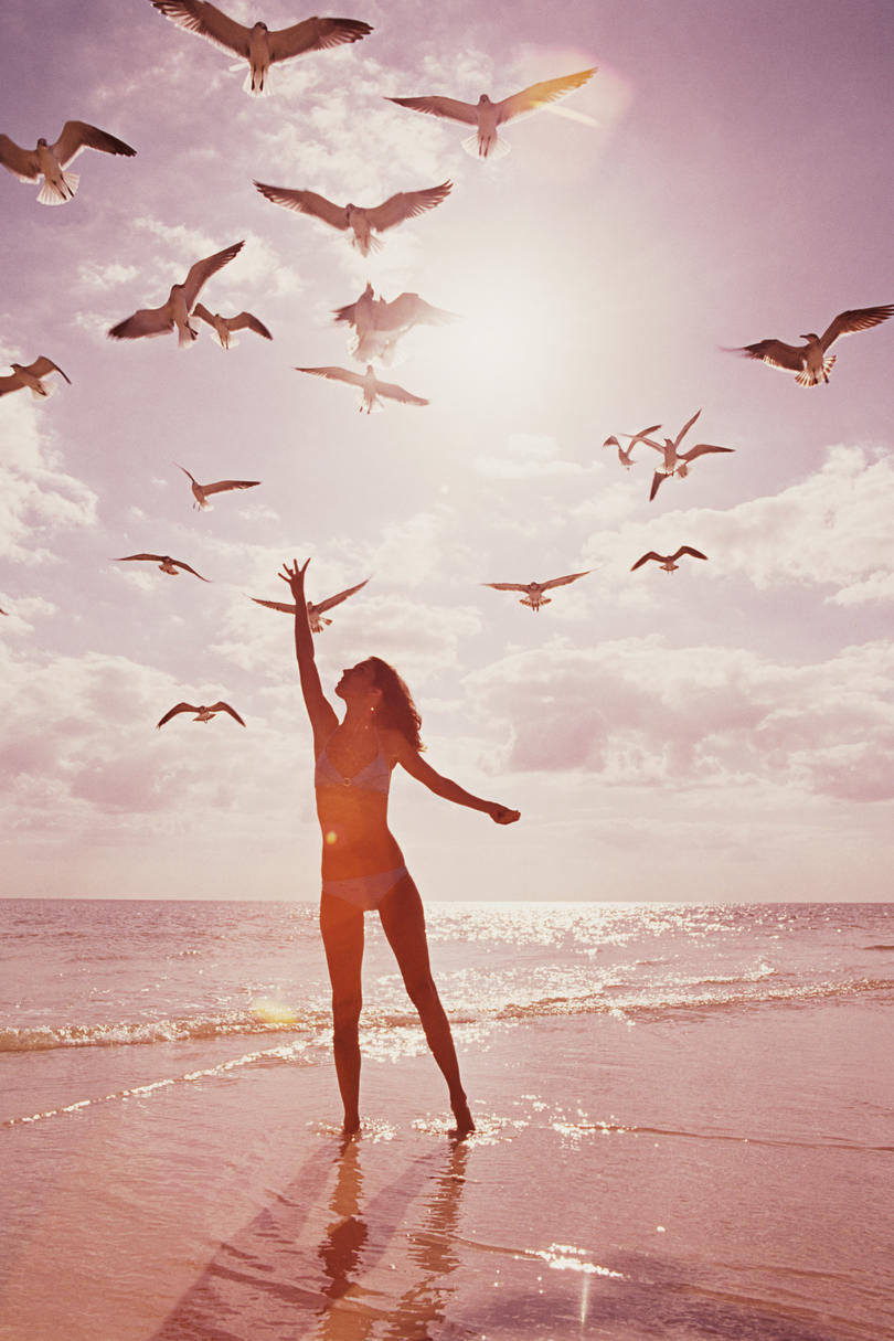 Mujer on beach reaching for seagulls
